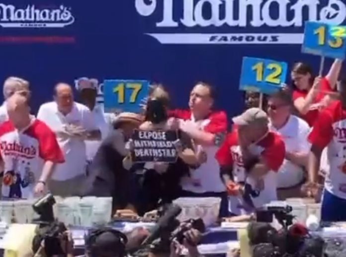 must-see:-hot-dog-eating-champ-joey-chestnut-chokes-out-animal-rights-protester-and-takes-him-to-the-ground-with-a-mouth-full-of-weiner-before-winning-contest-(video)